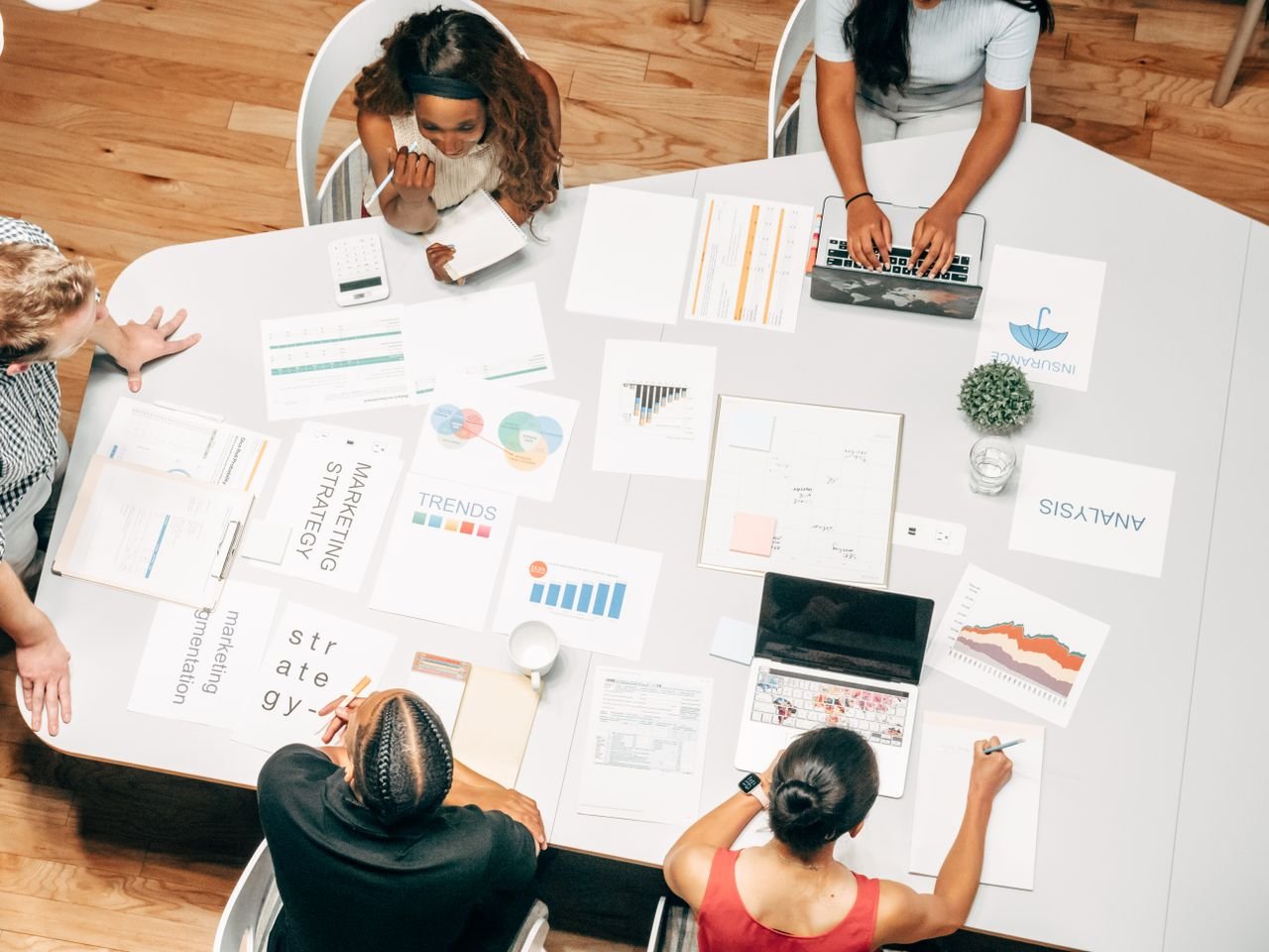Top view of a diverse team collaborating on marketing strategies around a white table.